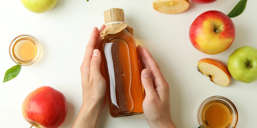 Hände greifen Flasche mit Apfelessig