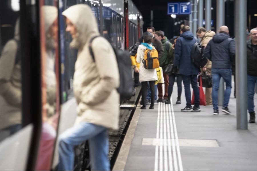 Pendlerinnen und Pendler steigen in einen Zug. Die Anschlüsse sind vielfach knapp berechnet – an Bahnhöfen führt das zu Hektik. (Symbolbild)