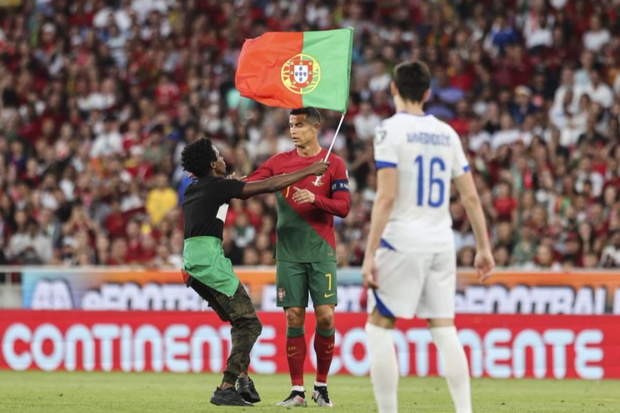 Ein Fan überrascht Cristiano Ronaldo beim EM-Quali-Spiel gegen Bosnien auf dem Platz.