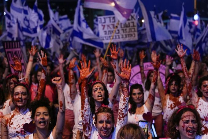 Israelische Aktivisten, die sich mit roter Farbe bespritzt haben, um auf die Gewalt gegen Frauen aufmerksam zu machen, nehmen an einem Protest gegen die Pläne der Regierung von Premierminister. Proteste