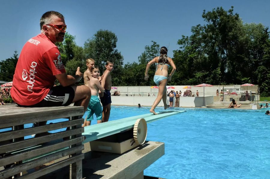 Chef-Badmeister Jean-Pierre von Gunten, rotes Shirt, überwacht das 25-Meter-Schwimmbecken, am Donnerstag, 17. Juli 2014, im Strandbad in Thun.