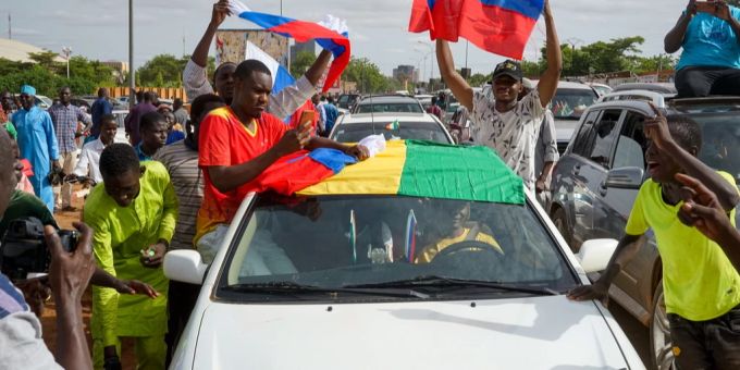 Anhänger der Militärregierung halten nigrische und russische Flaggen in die Luft. niger putsch neue regierung