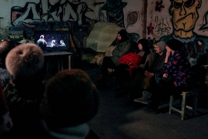 Der Strom kommt von einem Generator: In einem Keller eines Wohnhauses, der als Bunker genutzt wird, schauen sich Menschen einen religiösen Weihnachtsfilm an. Libkos/AP/dpa Ukraine-Krieg - Awdijiwka