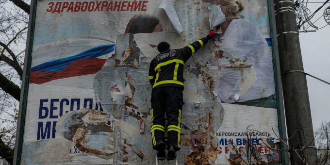 Ein ukrainischer Feuerwehrmann reisst in der kürzlich befreiten Stadt Cherson eine russisches Werbeplakat von einer Werbetafel. Ein ukrainischer Feuerwehrmann reisst in der kürzlich befreiten Stadt Cherson eine russisches Werbeplakat von einer Werbetafel.