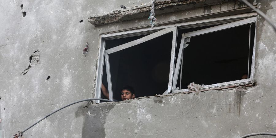 Ein kleiner palästinensischer Junge blickt aus dem Fenster eines zerstörten Gebäudes.