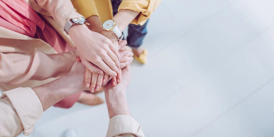 drei menschen halten die Hände zusammen, uhren am handgelenk, weisser untergrund