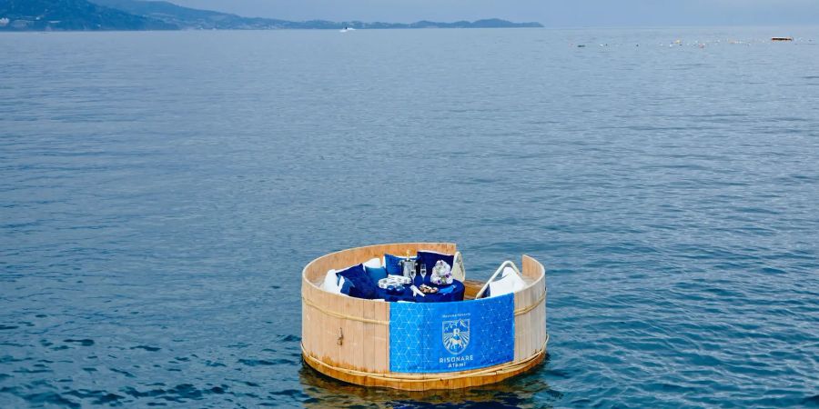 Rundes Holzfloss im Meer mit blauen Kissen.