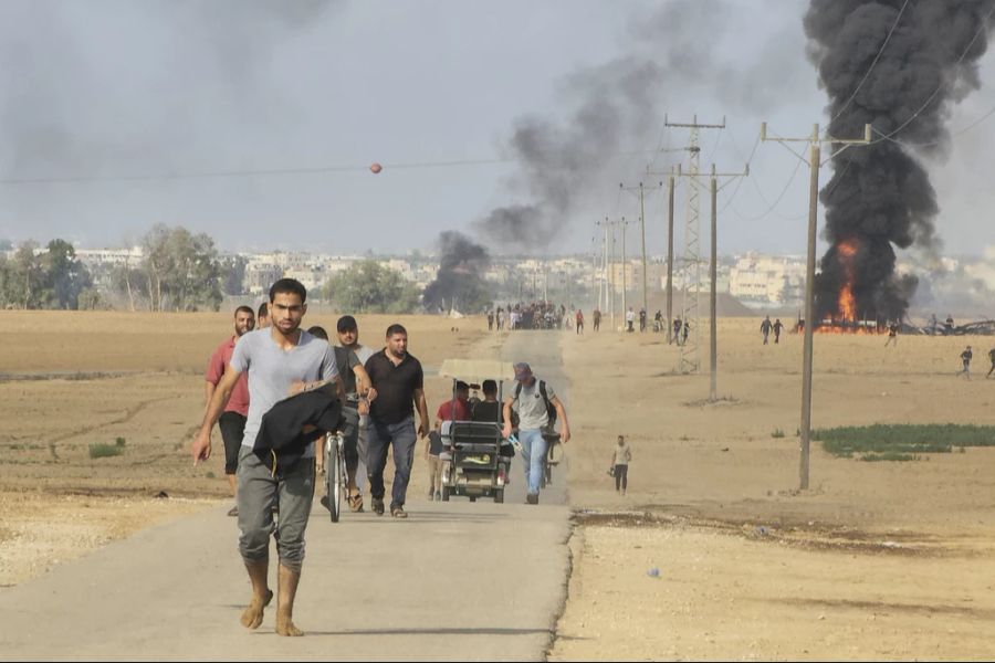 Palästinenser laufen vom Kibbuz «Kfar Azza» weg, in der Nähe des Zauns rund um den Gaza-Streifen, 7. Oktober 2023.