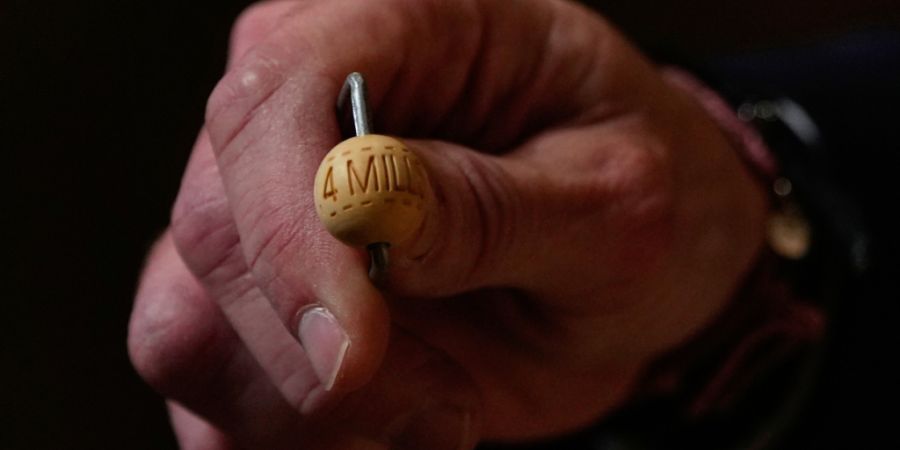 Ein Lottomitarbeiter zeigt eine Lottokugel vor der jährlichen Weihnachtslotterie-Ziehung, bekannt als El Gordo («Der Dicke»), im Madrider Teatro Real. Foto: Manu Fernandez/AP/dpa