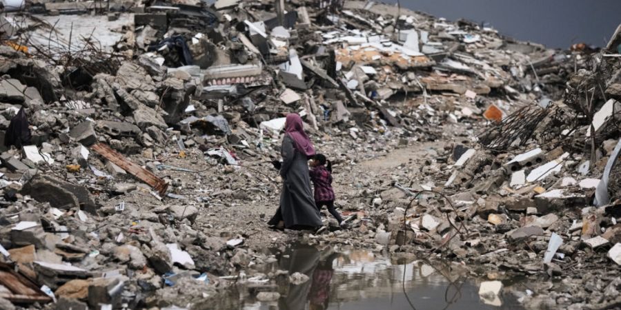 dpatopbilder - Palästinenser gehen bei stürmischem Wetter durch die Trümmer in Gaza. Foto: Jehad Alshrafi/AP/dpa