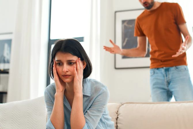 Nachdenkliche Frau, Mann schreit im Hintergrund