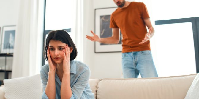 Nachdenkliche Frau, Mann schreit im Hintergrund