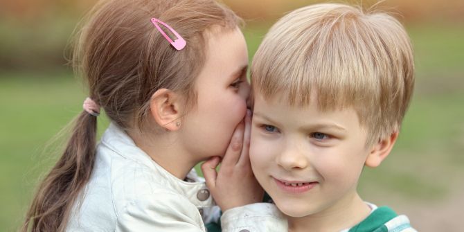 Mädchen flüstern Jungen etwas ins Ohr