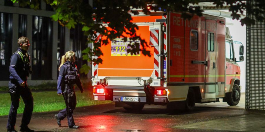 dpatopbilder - Polizisten laufen an einem ankommenden Rettungswagen vorbei, der eine deutsche Patientin in das Infektionszentrum der Uniklinik Düsseldorf bringt. Foto: Christoph Reichw...