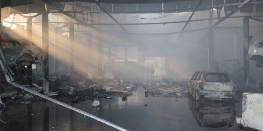 dpatopbilder - HANDOUT - Polizisten gehen durch eine Autowerkstatt in Saporischschja, die durch einen russischen Angriff zerstört wurde. Foto: Ukraine National Police/AP/dpa - ACHTUNG:...
