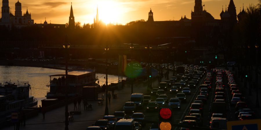 Autos fahren bei Sonnenuntergang am Moskvoretskaya-Ufer des Moskwa-Flusses entlang, im Hintergrund der Kreml. Foto: Alexander Zemlianichenko/AP/dpa