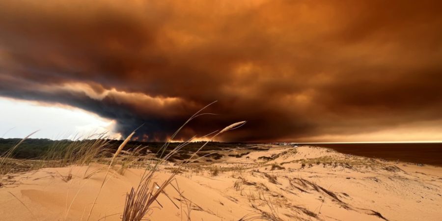 dpatopbilder - Rauchwolken von den Waldbränden südöstlich des Badeortes Lacanau-Ocean (hinten, r) verdunkeln den Himmel, während sie über die Dünen am Nordstrand hinwegziehen. Fot...