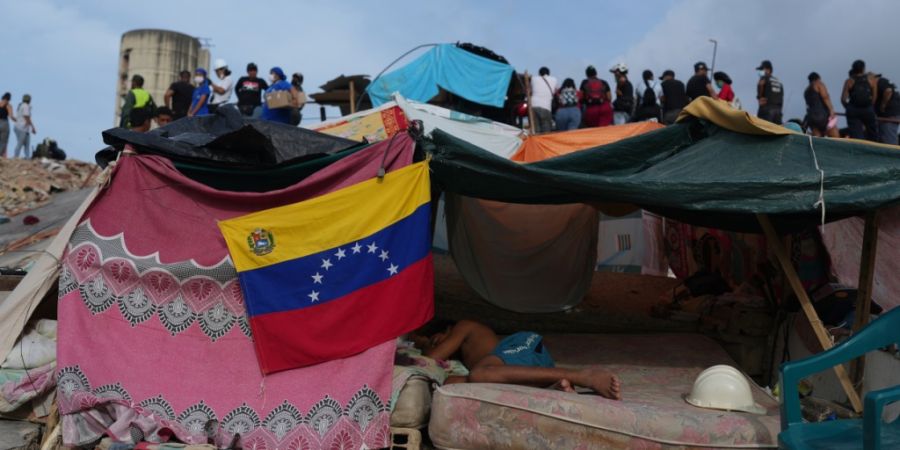ARCHIV - Ein junger Mann schläft in einer Behausung, während Rettungskräfte nach den Erdbeben in La Guaira, Venezuela, weiter in den Trümmern suchen. Foto: Ariana Cubillos/AP/dpa