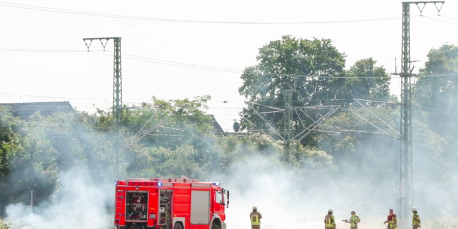 dpatopbilder - Feuerwehrleute bei Löscharbeiten an einer Bahnstrecke. Foto: Patrick Schüller/dpa