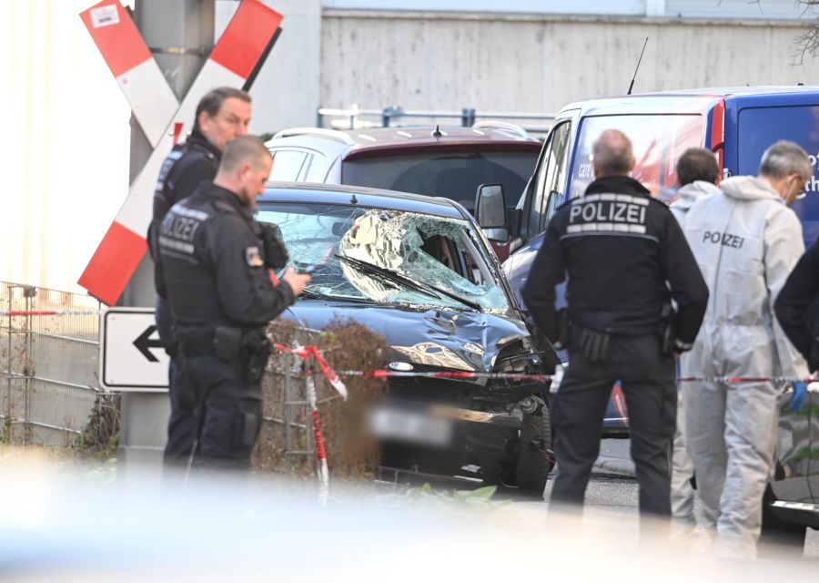 Einsatzkräfte der deutschen Polizei stehen bei dem Grosseinsatz neben einem beschädigten Fahrzeug in Mannheim (D). (Archivbild)