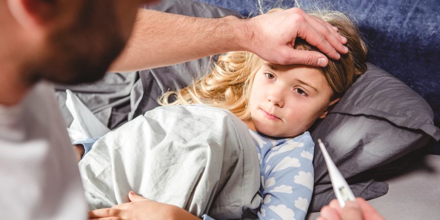 Krankes kleines Mädchen im Bett. Fieber messen.