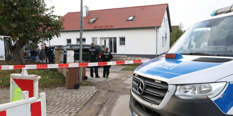 Ein Polizeifahrzeug steht an einer mit Flatterband abgesperrten Straße vor einem Tatort. Ein 60-jähriger Mann soll bei einer routinemäßigen Waffenkontrolle eine Mitarbeiterin und ei...