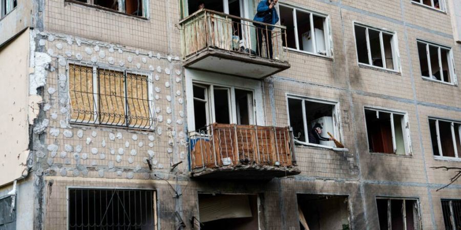 Ein Mann steht auf dem Balkon eines Wohnhauses, das durch einen russischen Drohnenangriff beschädigt wurde. Foto: Evgeniy Maloletka/AP/dpa