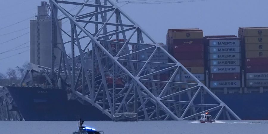 Ein Containerschiff liegt bei Einbruch der Dunkelheit am Wrack der Francis Scott Key Bridge. Foto: Matt Rourke/AP