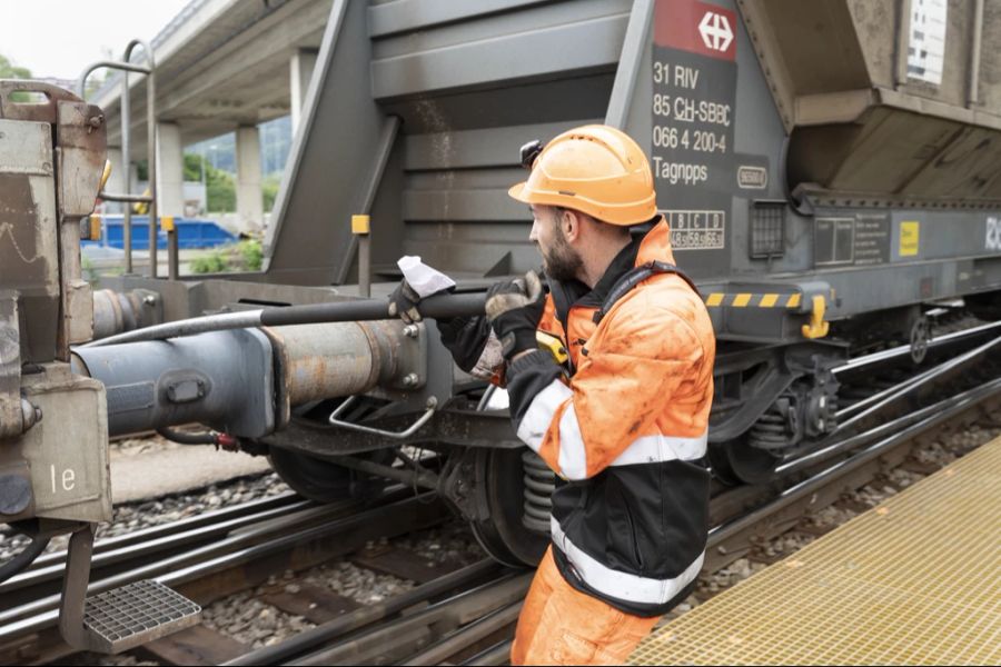 Ein Rangierarbeiter entkuppelt zwei Wagen.