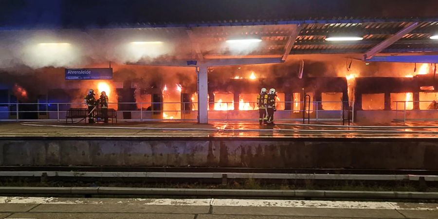 Einsatzkräfte der Feuerwehr löschen den Brand eines Zuges im S-Bahnhof Ahrensfelde.