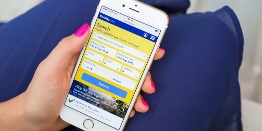 Frau hält Smartphone mit geöffneter App von Booking.com