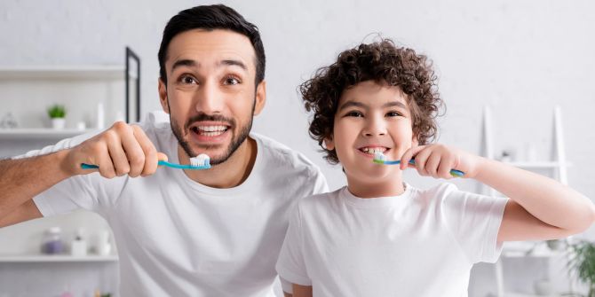 vater putzt mit seinem sohn die zähne, badezimmer, weisser hintergrund