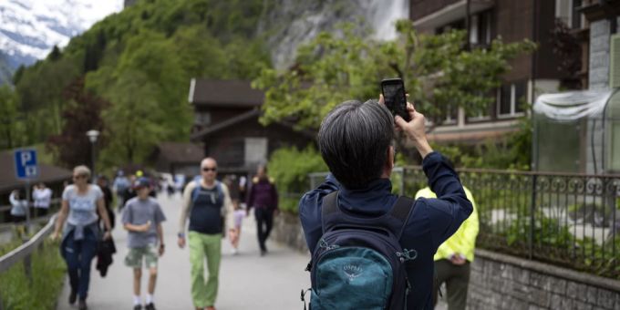 Ein Tourist fotografiert ein Haus im Dorf Lauterbrunnen im Berner Oberland, am Sonntag, 19. Mai 2024. Touristen Schweiz