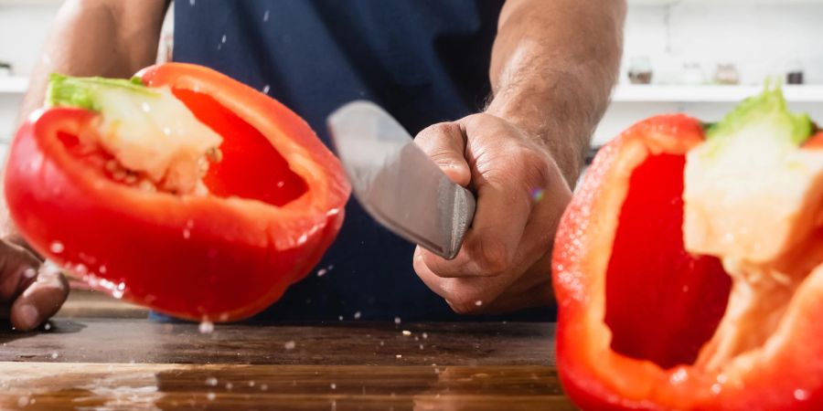 Aufgeschnittene Paprika mit Mann mit Messer im Hintergrund