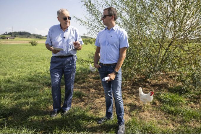 Bundesrat Guy Parmelin, links, spricht neben Bauer Christoph Herren und einem von 12'000 Hühnern auf dessen Bauerngut zu Medienleuten, am 16. August 2024 in Wileroltigen BE. Guy Parmelin Christoph Herren