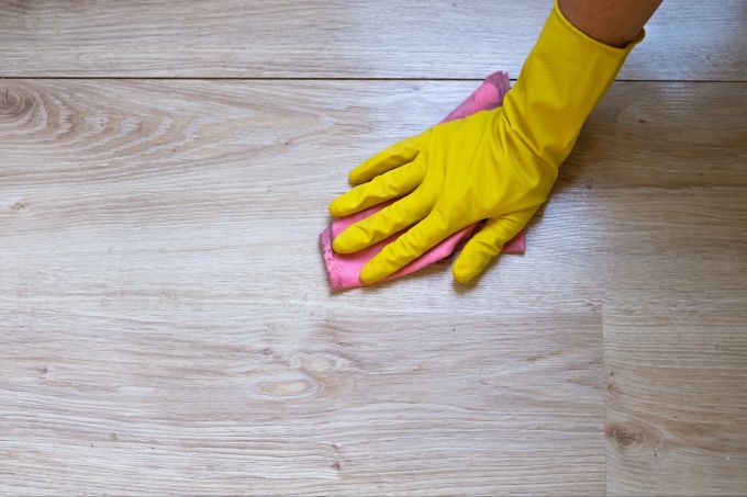 Zu viel Feuchtigkeit ist bei Holz- und Laminatböden keine gute Idee, da das Material empfindlich reagiert. Reinigung eines Laminatbodens mit Handschuh und Tuch