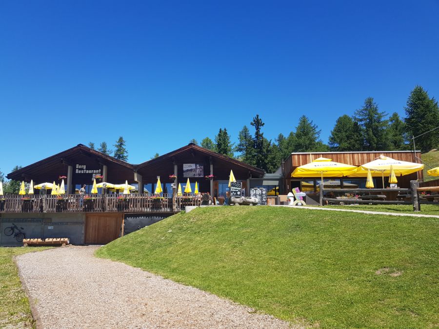 Bergrestaurant Rasenfläche Sonnenschirme Wald Gelände