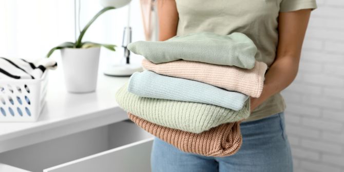 Frau mit gefalteten, gestapelten Pullovern