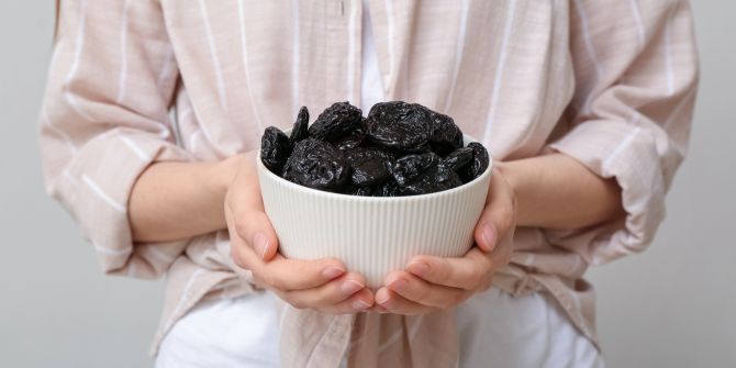 Person hält Schüssel mit Trockenpflaumen