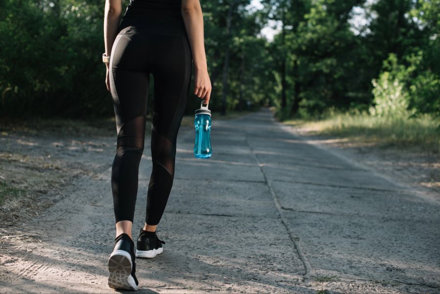 Beine einer Frau beim Walken, Wasserflasche