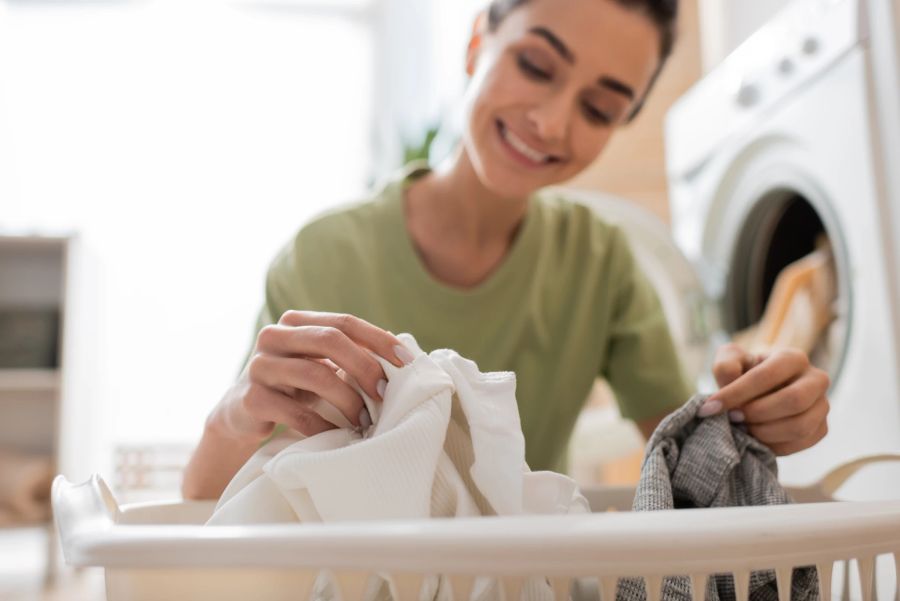 Frau mit Kleidung vor Waschmaschine