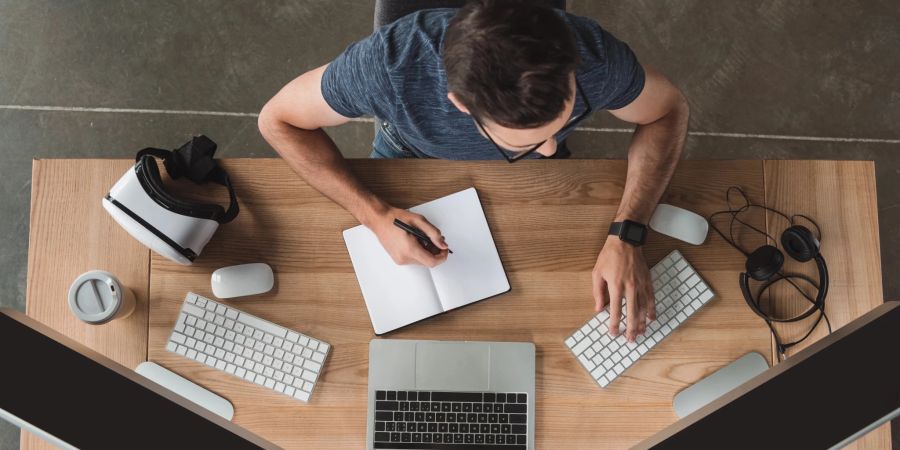 Junger Mann sitzt am digitalen Arbeitsplatz