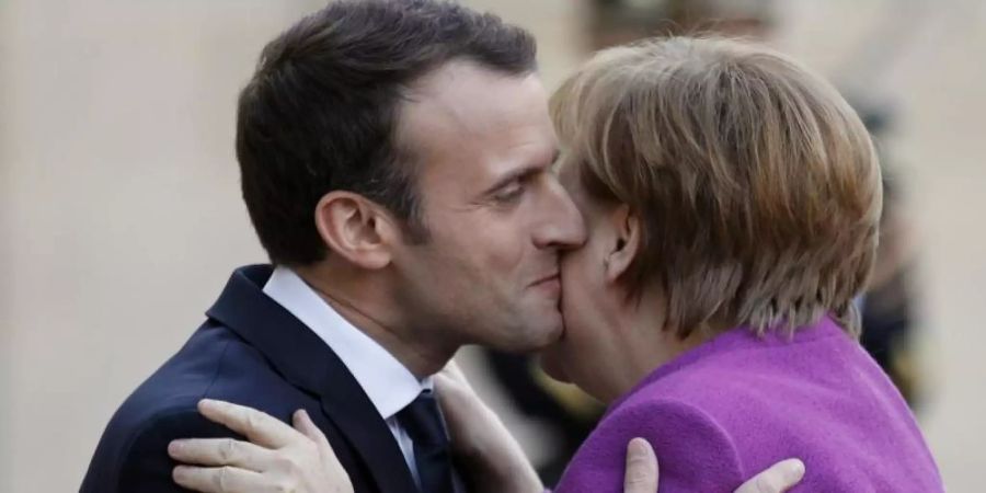 Frankreichs Präsident Emmanuel Macron und Noch-Bundeskanzlerin Angela Merkel geben sich Küsschen. Foto: Francois Mori/AP/dpa