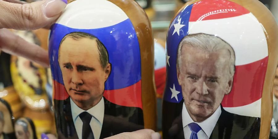 Eine Kundin eines Souvenirladens zeigt dem Fotografen traditionelle russische Holzpuppen (Matrjoschkas), auf denen Wladimir Putin (l), Präsident von Russland, und Joe Biden, Präsident der USA, zu sehen sind. Foto: Pavel Golovkin/AP/dpa