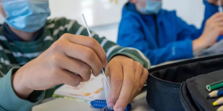 Münchner Schüler machen zu Beginn des Unterrichts einen Covid-19-Schnelltest. Die 7-Tage-Inzidenz in Deutschland ist am vierten Tag in Folge etwas gestiegen. Foto: Peter Kneffel/dpa