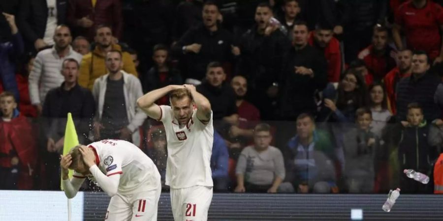 Polen Spieler schützen sich vor den Flaschenwürfen der albanischen Anhänger. Foto: Franc Zhurda/AP/dpa