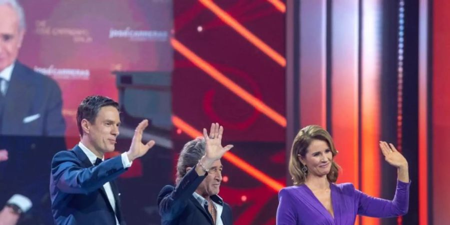 Moderatorin Mareile Höppner und Moderator Sven Lorig (l) stehen während der José Carreras Gala in Leipzig gemeinsam mit dem Sänger Peter Maffay auf der Bühne. Foto: Hendrik Schmidt/dpa-Zentralbild/dpa