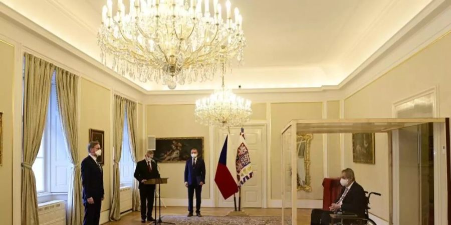 Der tschechische Präsident Milos Zeman (r) sitzt während der Vereidigung von Petr Fiala (l) in einem Rollstuhl hinter einer durchsichtigen Wand. Foto: Roman Vondrous/CTK/AP/dpa