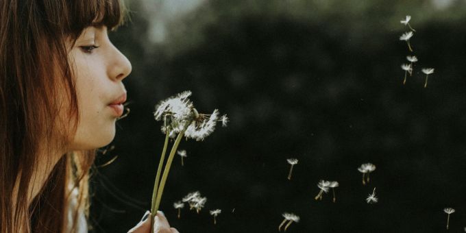 Manifestieren bedeutet, Gedanken zur Realität zu machen. Frau bläst Blume