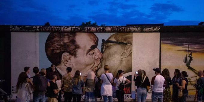 Touristen und Besucher stehen vor dem sogenannten «Bruderkussgemälde» an der East Side Gallery. Vor fast 30 Jahren hatten sich hier Künstler verewigt und das längste noch erhaltene Teilstück der Berliner Mauer mit ihren Kunstwerken umgedeutet. Foto: Arne Immanuel Bänsch Touristen und Besucher stehen vor dem sogenannten «Bruderkussgemälde» an der East Side Gallery. Vor fast 30 Jahren hatten sich hier Künstler verewigt und das längste noch erhaltene Teilstück der Berliner Mauer mit ihren Kunstwerken umgedeutet. Foto: Arne Immanuel Bänsch